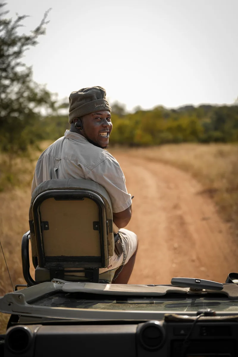 A guide seated in the raised tracker's seat on the front of a safari vehicle
