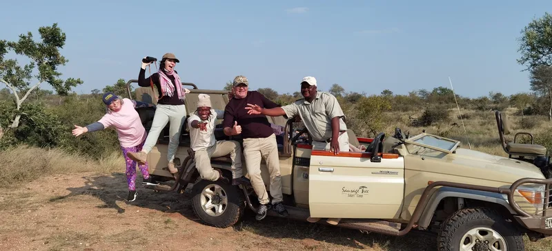 Guests standing on the back of a safari vehicle, watching something in the distance