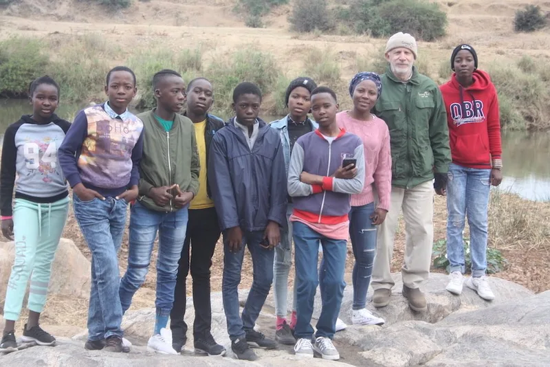 a group of people standing next to each other in front of a body of water .