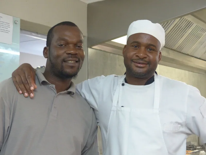Two members of the camp team standing together, one in chef's whites, smiling