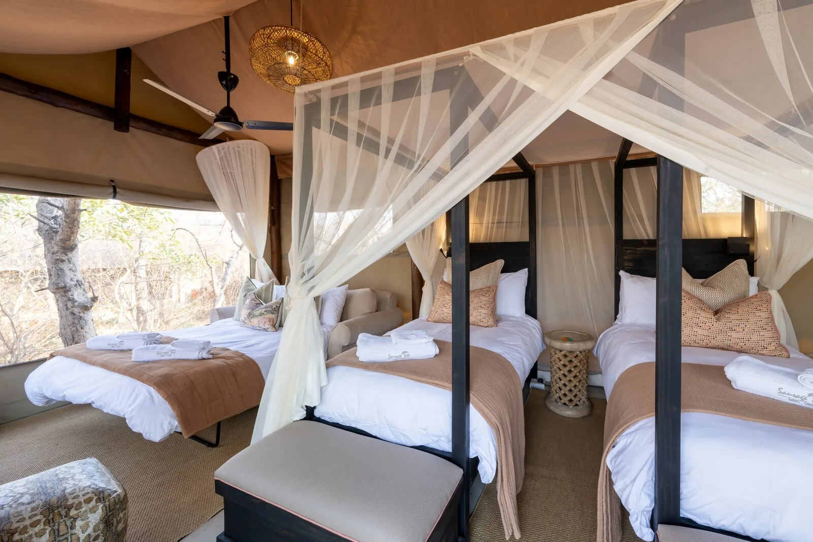 Warm-lit four-poster bed in a Luxury Tented Suite at Sausage Tree