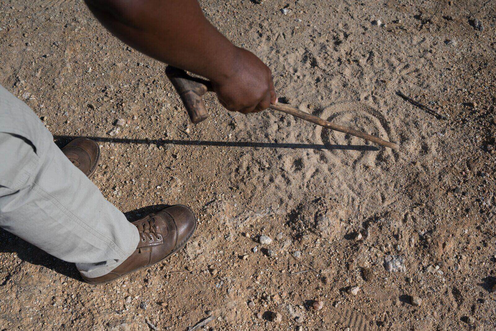 Tracker's hands pointing at fresh spoor in soft sand